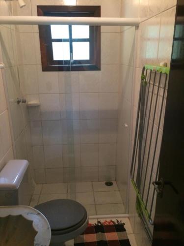 baño con ducha, aseo y ventana en Apartamento em Condomínio Praia de Boiçucanga Litoral Norte en Boicucanga