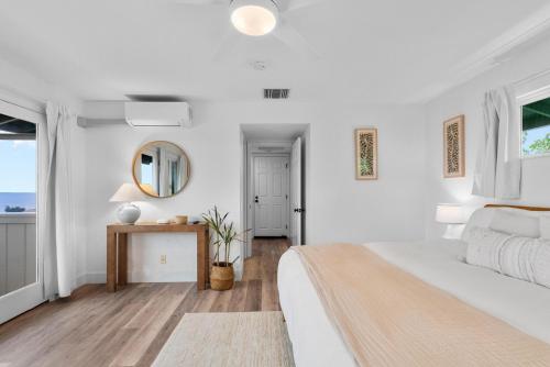 a white bedroom with a bed and a mirror at Kona Kai Ocean View Suite in Kailua-Kona