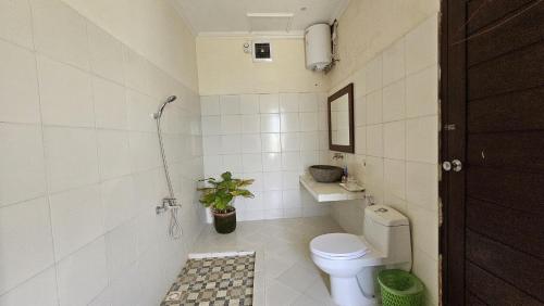 a bathroom with a toilet and a plant in it at Rosella Cottages - Homestay - Yogyakarta in Yogyakarta