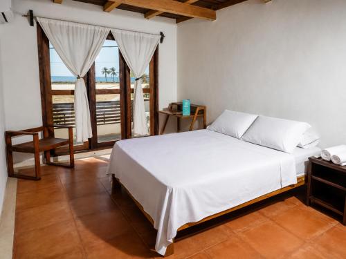 a bedroom with a white bed and a balcony at Hotel Verdemar in Acapulco