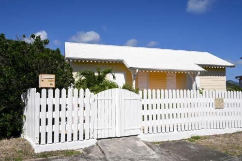 a white fence in front of a white house at L'escapade in Sainte-Anne