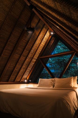 a bed in a room with a large window at RONJA Boutique Hotel - Adults Only in Uluwatu