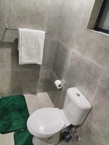 a bathroom with a white toilet and towels at Phumlani Village Lodge in White River