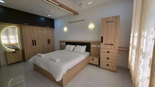 a bedroom with a large white bed with wooden cabinets at Science House Lux Inn in Kadayirippu