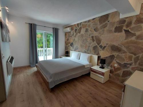 a bedroom with a bed and a stone wall at Muo Suntime apartment in Muo
