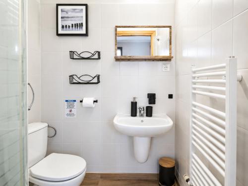 a white bathroom with a toilet and a sink at Pensjonat Natalia Sarbinowo - Blisko Plaży in Sarbinowo