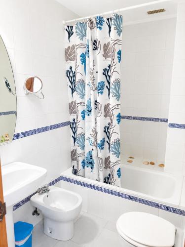 a bathroom with a toilet and a shower curtain at Casa Denver in El Rompido