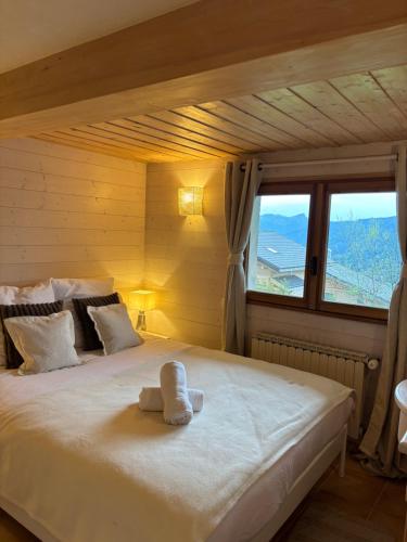 a bedroom with a large white bed with a window at Charmant appartement avec jardin et magnifique vue in Saint-Jean-de-Sixt