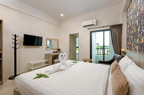 a hotel room with a white bed and a tv at Ang Pao Hotel Phuket in Phuket
