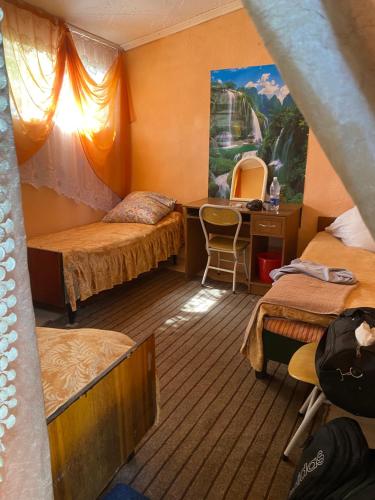 a room with two beds and a desk with a mirror at уют in Cholpon-Ata