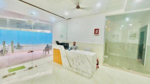a woman sitting at a reception desk in a room at Sai Sansthan Inn in Lucknow
