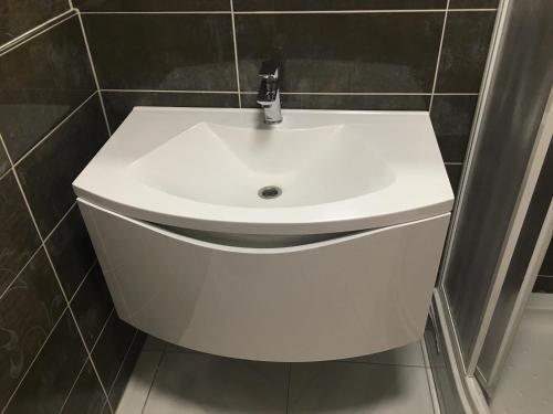 a white sink in a bathroom with black tiles at Rooms & Apartments Banjac in Maribor