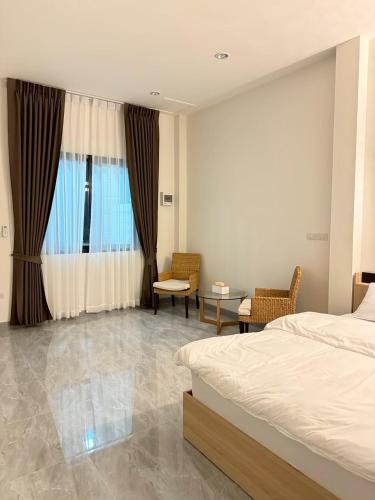 a bedroom with a bed and chairs and a window at KlomKlom garden home in Ban Tha Kham