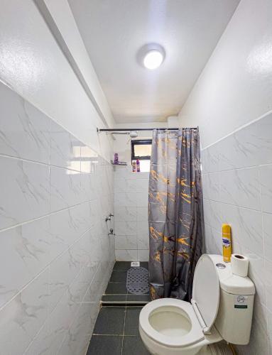 a bathroom with a toilet and a shower curtain at The Escape Muthiga Waiyaki way in Nairobi