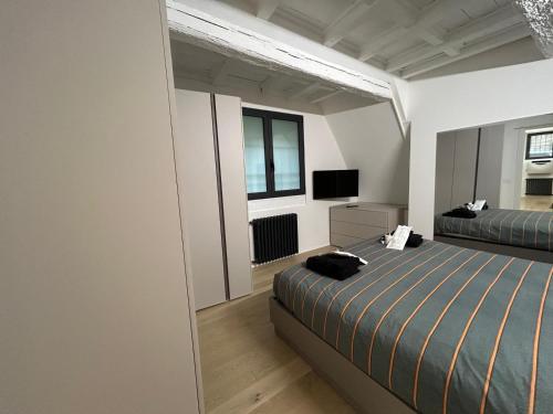 a bedroom with two beds and a flat screen tv at La casa Arancio in Ferrara