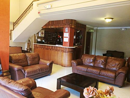 a living room with leather couches and a bar at Gran Hotel Marcjohns in Catamayo