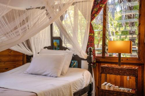 a bedroom with a canopy bed with a window at Cliffside Amani Wooden Villa with Stunning Ocean Views for an Authentic Tanzanian Escape in Dar es Salaam