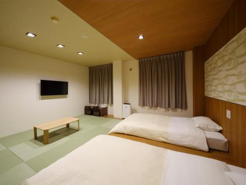 a bedroom with a bed and a table and a tv at Isahaya Daiichi Hotel in Isahaya