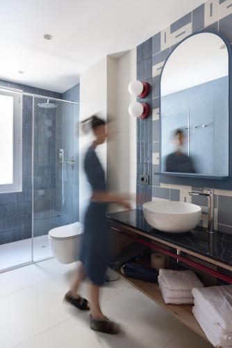 a woman in a bathroom with a sink and a mirror at Casa Merano Residence & Restaurant Bibione Centro in Bibione
