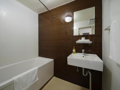 a bathroom with a sink and a bath tub and a mirror at Isahaya Daiichi Hotel in Isahaya