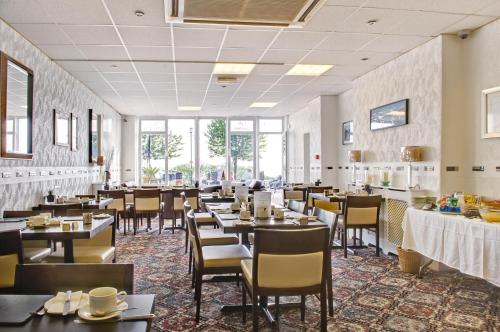 a dining room with tables and chairs and windows at The Downs, Babbacombe in Torquay