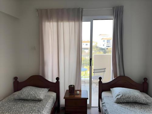 a bedroom with two beds and a large window at Stay in Harmony in Paralimni