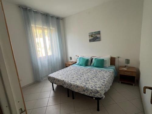 a bedroom with a bed with blue pillows and a window at Appartamento Ortensia in Fetovaia