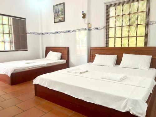 a bedroom with two beds with white sheets at Bungalow COCO CHILL PQ in Phú Quốc
