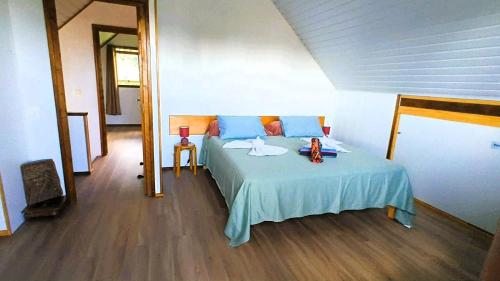 a bedroom with a bed with a blue bedspread and a table at Chalet Familiale Vue Mer et Coucher de Soleil Moorea in Moorea