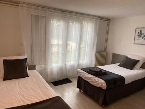a bedroom with two beds and a window with curtains at Auberge de Lamagistere in Lamagistère