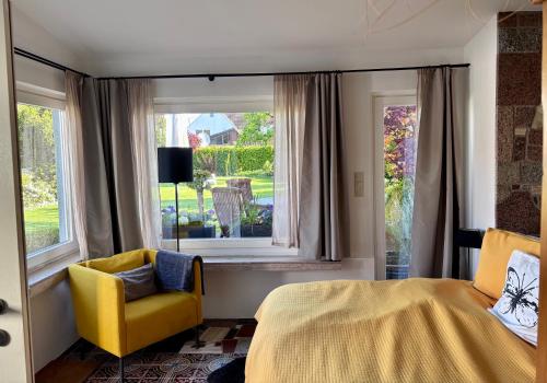 a bedroom with a bed and a yellow chair and a window at Tiny house with charm in Bremen