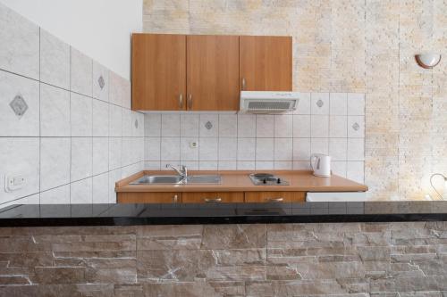 a kitchen with a sink and wooden cabinets at Apartmani Petracie in Drvenik