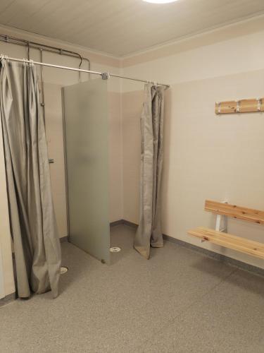 a bathroom with a shower with curtains and a bench at Your cottege by the sea in Saltvik