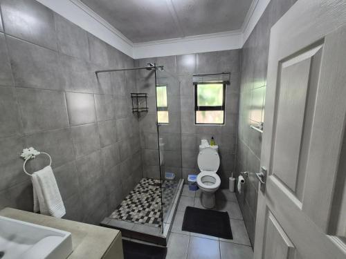 a bathroom with a shower with a toilet and a sink at Next to Heaven Guesthouse in Stormsrivier