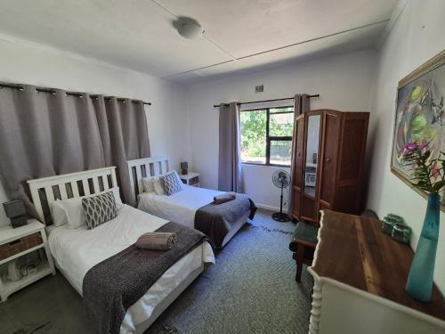 a bedroom with two beds and a desk and a window at Next to Heaven Guesthouse in Stormsrivier