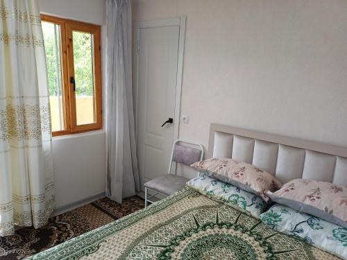 a bedroom with a bed and a window and a chair at " UMAR " Guest house in Tong