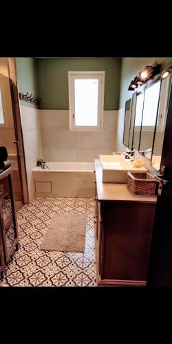a bathroom with a sink and a tub and a mirror at Maison paisible en lisière de foret 9 personnes in Le Temple