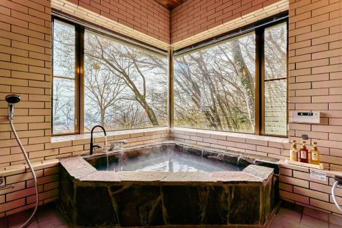 a large stone tub in a room with windows at NASU Fir Tree in Nasu