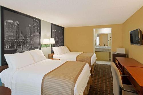 a hotel room with two beds and a desk at Rodeway Inn Charlotte Airport Area in Charlotte