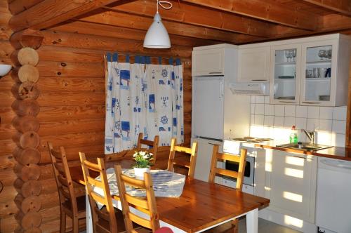 eine Küche und ein Esszimmer mit einem Tisch und Stühlen in der Unterkunft Hotel Hanhi Cottages in Lapinjärvi
