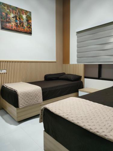 a bedroom with two beds and a painting on the wall at Homestay Berlian T in Alastuwo