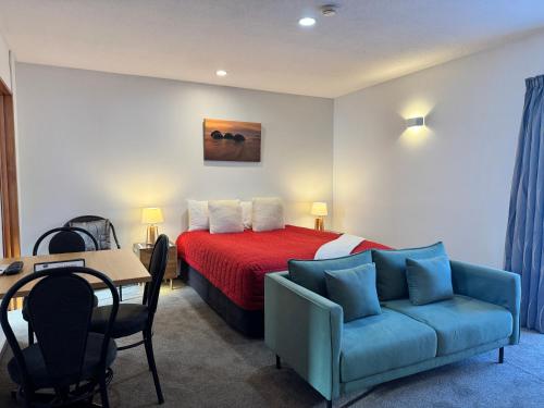 a bedroom with a bed and a table and a couch at ASURE Ambassador Motor Lodge in Oamaru
