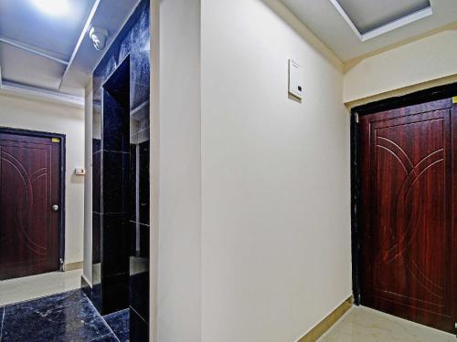 a hallway with two wooden doors and a walk in shower at Hotel O ASHIRBAD PALACE in Urāli