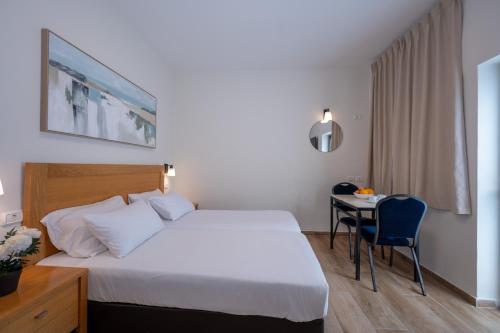 a hotel room with a bed and a desk with a table at מלון ברגר - למגזר החרדי in Tiberias