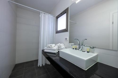 a white bathroom with a sink and a mirror at מלון ברגר - למגזר החרדי in Tiberias