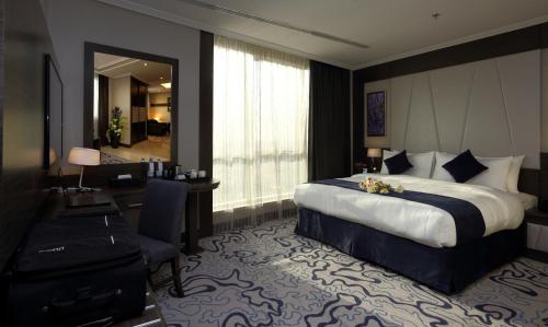 a hotel room with a large bed and a desk at Swiss Flora Royal Hotel Riyadh in Riyadh