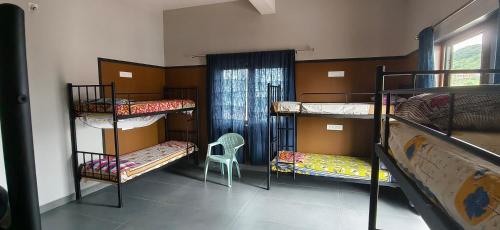 a room with three bunk beds and a chair at Belmonte in Kalasa