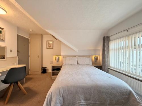 a bedroom with a bed and a desk and a window at Avenue Guest House in Blackpool