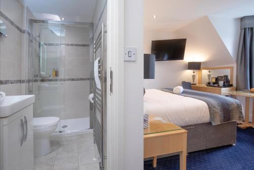 a hotel room with a bed and a bathroom at Belgrave Sands Hotel & Spa in Torquay