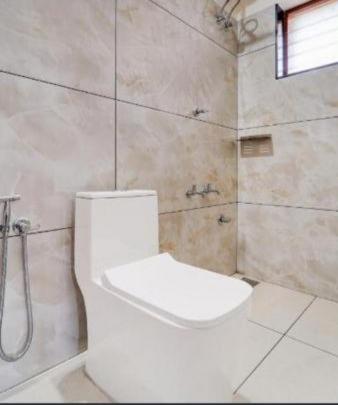 a bathroom with a toilet and a shower at Blanco Airport Suite in Kāladi